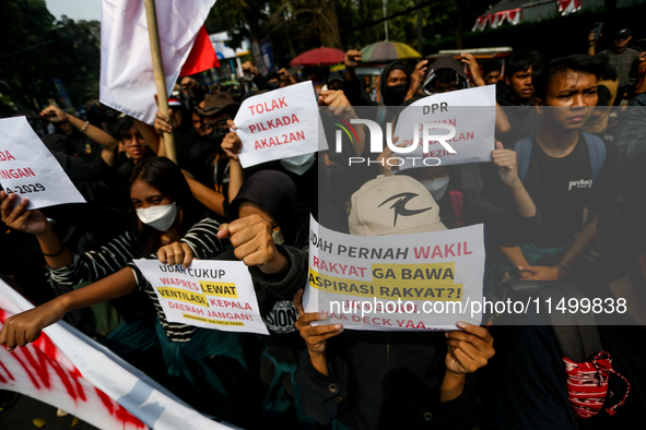 Students hold protest posters during a demonstration to reject the ratification of the Regional Head Election (Pilkada) Bill in front of the...