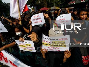 Students hold protest posters during a demonstration to reject the ratification of the Regional Head Election (Pilkada) Bill in front of the...