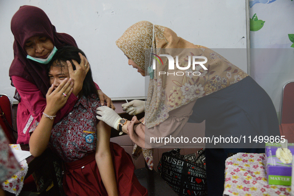 A health worker prepares to inject a dose of the Human Papilloma Virus (HPV) vaccine into a schoolgirl's arm during the Immunization Month f...