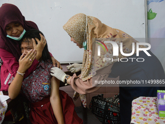 A health worker prepares to inject a dose of the Human Papilloma Virus (HPV) vaccine into a schoolgirl's arm during the Immunization Month f...