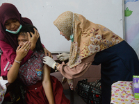 A health worker prepares to inject a dose of the Human Papilloma Virus (HPV) vaccine into a schoolgirl's arm during the Immunization Month f...