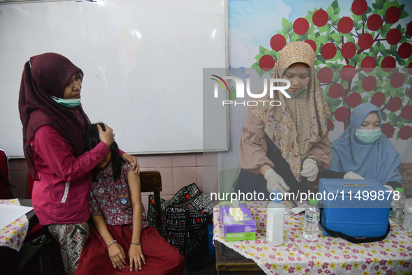 A health worker prepares to inject a dose of the Human Papilloma Virus (HPV) vaccine into a schoolgirl's arm during the Immunization Month f...