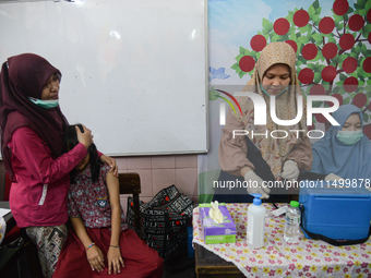 A health worker prepares to inject a dose of the Human Papilloma Virus (HPV) vaccine into a schoolgirl's arm during the Immunization Month f...