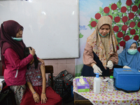 A health worker prepares to inject a dose of the Human Papilloma Virus (HPV) vaccine into a schoolgirl's arm during the Immunization Month f...