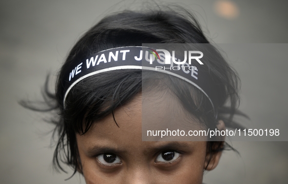 A child poses in front of a camera, wearing a hair band that reads ''WE WANT JUSTICE,'' as part of a protest against the rape and murder of...