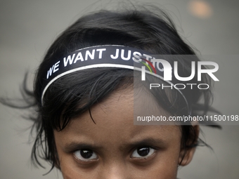 A child poses in front of a camera, wearing a hair band that reads ''WE WANT JUSTICE,'' as part of a protest against the rape and murder of...