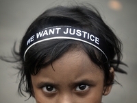 A child poses in front of a camera, wearing a hair band that reads ''WE WANT JUSTICE,'' as part of a protest against the rape and murder of...