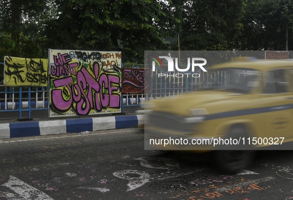 A yellow taxi passes a graffiti poster that reads ''WE WANT JUSTICE'' as part of a protest against the rape and murder of a trainee medic at...