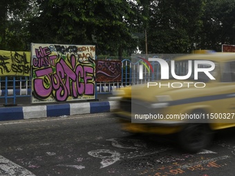 A yellow taxi passes a graffiti poster that reads ''WE WANT JUSTICE'' as part of a protest against the rape and murder of a trainee medic at...