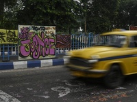 A yellow taxi passes a graffiti poster that reads ''WE WANT JUSTICE'' as part of a protest against the rape and murder of a trainee medic at...