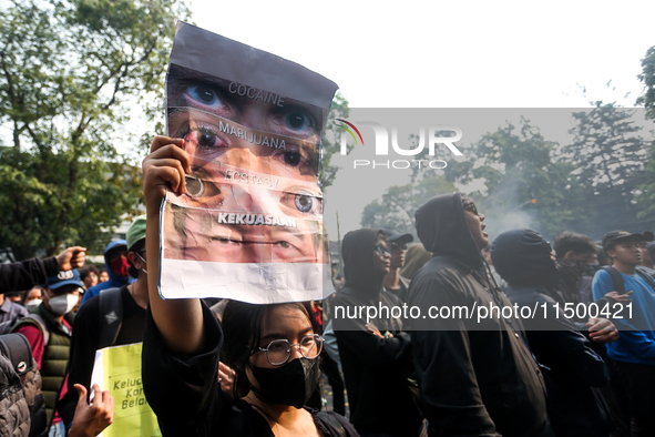 A woman holds a protest poster during a demonstration to reject the revised Regional Head Election Bill (RUU) in front of the West Java DPRD...