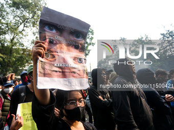 A woman holds a protest poster during a demonstration to reject the revised Regional Head Election Bill (RUU) in front of the West Java DPRD...