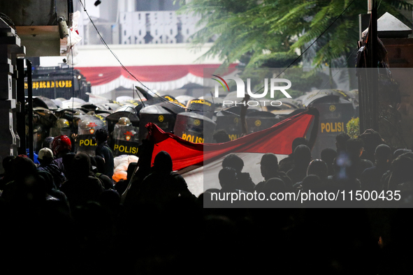 Thousands of demonstrators clash with police while holding Indonesian flags during a protest against the revision of the Regional Head Elect...