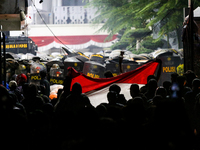 Thousands of demonstrators clash with police while holding Indonesian flags during a protest against the revision of the Regional Head Elect...