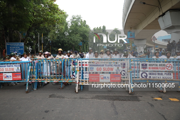 The police force stands guard behind the police barricade to stop Bharatiya Janata Party (BJP) activists as they go towards the State Health...