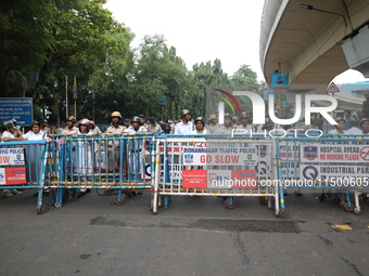 The police force stands guard behind the police barricade to stop Bharatiya Janata Party (BJP) activists as they go towards the State Health...