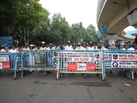 The police force stands guard behind the police barricade to stop Bharatiya Janata Party (BJP) activists as they go towards the State Health...