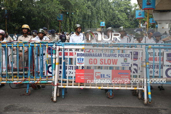 The police force stands guard behind the police barricade to stop Bharatiya Janata Party (BJP) activists as they go towards the State Health...