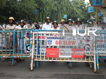 The police force stands guard behind the police barricade to stop Bharatiya Janata Party (BJP) activists as they go towards the State Health...