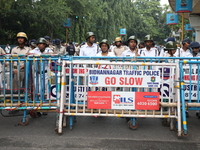 The police force stands guard behind the police barricade to stop Bharatiya Janata Party (BJP) activists as they go towards the State Health...