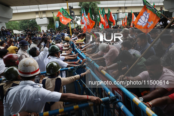 Bharatiya Janata Party (BJP) activists shout slogans and try to break the police barricade during a protest rally as they go towards the Sta...