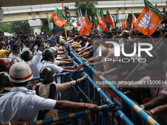 Bharatiya Janata Party (BJP) activists shout slogans and try to break the police barricade during a protest rally as they go towards the Sta...