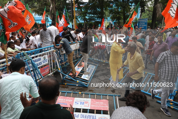 Bharatiya Janata Party (BJP) activists shout slogans and break the police barricade during a protest rally as they go towards the State Heal...