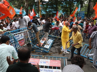 Bharatiya Janata Party (BJP) activists shout slogans and break the police barricade during a protest rally as they go towards the State Heal...