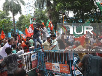 Bharatiya Janata Party (BJP) activists shout slogans and break the police barricade during a protest rally as they go towards the State Heal...