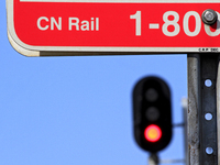 A CN Rail sign shows in front of a red signal light at a level crossing on the same rail corridor through the Brampton Innovation District t...