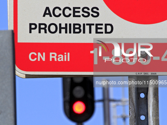 A CN Rail sign shows in front of a red signal light at a level crossing on the same rail corridor through the Brampton Innovation District t...