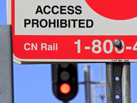 A CN Rail sign shows in front of a red signal light at a level crossing on the same rail corridor through the Brampton Innovation District t...