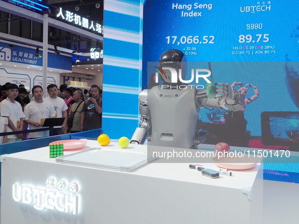 Visitors watch a robot grasping performance at the 2024 World Robot Conference in Beijing, China, on August 22, 2024. 