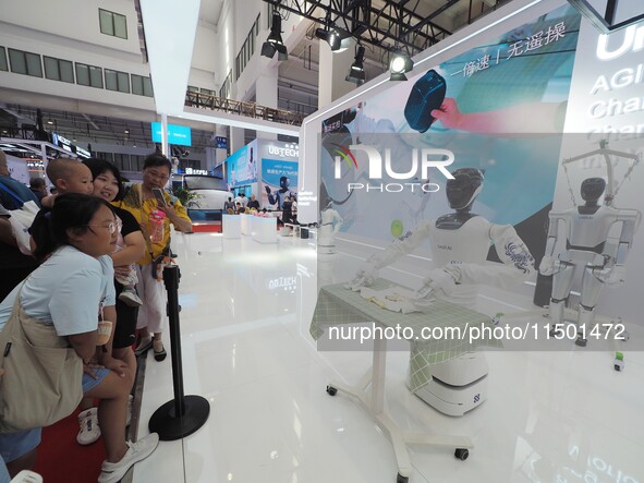 Visitors watch a robot fold clothes during the 2024 World Robot Conference in Beijing, China, on August 22, 2024. 