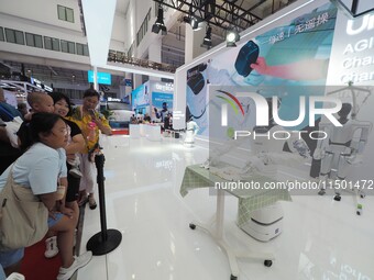 Visitors watch a robot fold clothes during the 2024 World Robot Conference in Beijing, China, on August 22, 2024. (