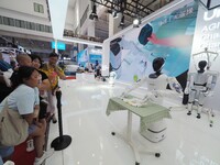 Visitors watch a robot fold clothes during the 2024 World Robot Conference in Beijing, China, on August 22, 2024. (