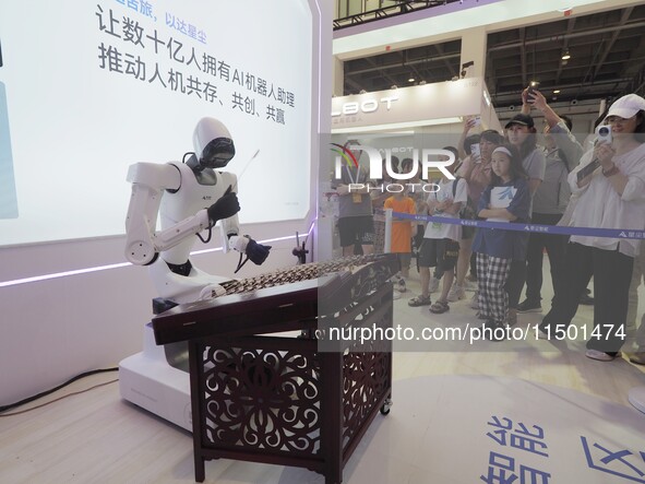 Visitors watch a ''humanoid robot'' play the dulcimer at the 2024 World Robot Conference in Beijing, China, on August 22, 2024. 