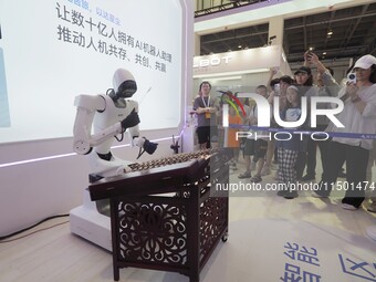 Visitors watch a ''humanoid robot'' play the dulcimer at the 2024 World Robot Conference in Beijing, China, on August 22, 2024. (