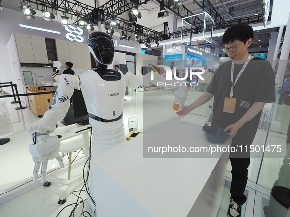 Visitors watch a robot grasping performance at the 2024 World Robot Conference in Beijing, China, on August 22, 2024. 