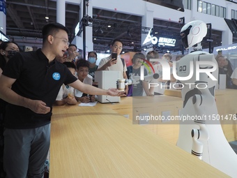 Visitors interact with a home service robot at the 2024 World Robot Conference in Beijing, China, on August 22, 2024. (