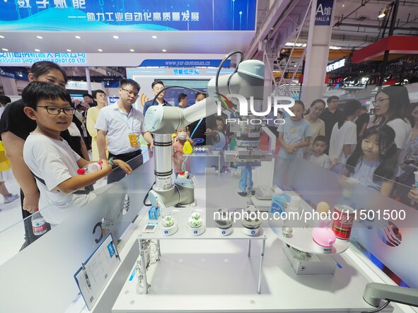 Visitors visit a ''picking and weighing robot'' at the 2024 World Robot Conference in Beijing, China, on August 22, 2024. 