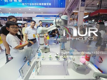 Visitors visit a ''picking and weighing robot'' at the 2024 World Robot Conference in Beijing, China, on August 22, 2024. (