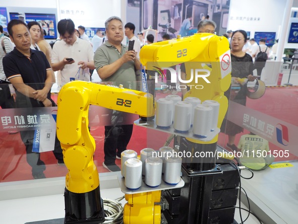 Visitors visit the ''three-machine linkage winding can'' at the 2024 World Robot Conference in Beijing, China, on August 22, 2024. 