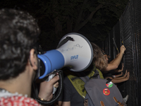 Protesters try to breach the security fence at George Washington University in Washington, D.C., United States, on August 22, 2024, while jo...