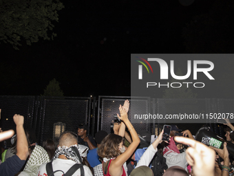 Protesters try to breach the security fence at George Washington University in Washington, D.C., United States, on August 22, 2024, while jo...