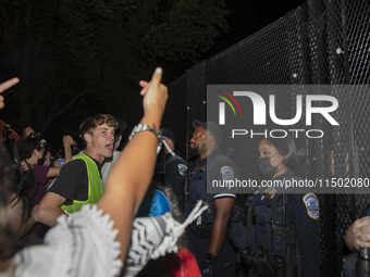 Police officers stop protesters from breaking the fence at George Washington University in Washington, D.C., on August 22, 2024, during a pr...