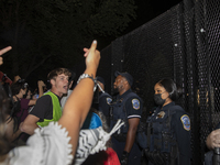 Police officers stop protesters from breaking the fence at George Washington University in Washington, D.C., on August 22, 2024, during a pr...