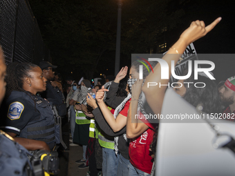 Police officers stop protesters from breaking the fence at George Washington University in Washington, D.C., on August 22, 2024, during a pr...