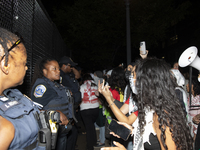 Police officers stop protesters from breaking the fence at George Washington University in Washington, D.C., on August 22, 2024, during a pr...