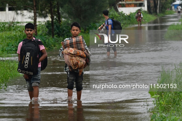 People wade through floodwater in Feni, Chittagong, Bangladesh, on August 23, 2024. 